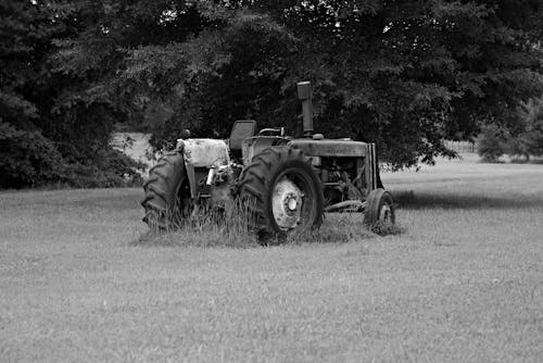 Grayscale Photo of a Tractor on a Grassy Field