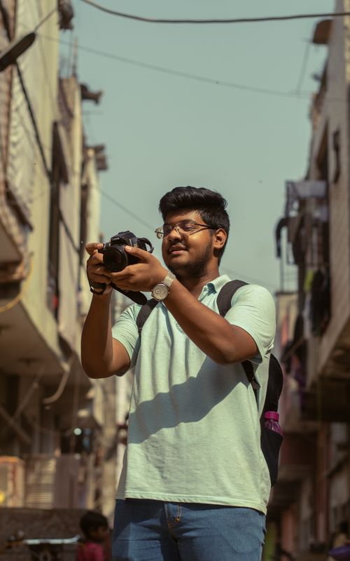 Free A young man in India photographs urban street scenes, capturing the vibrant local culture. Stock Photo