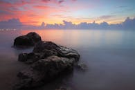 平静的海水映衬着宁静的海景、岩石和充满活力的日落天空