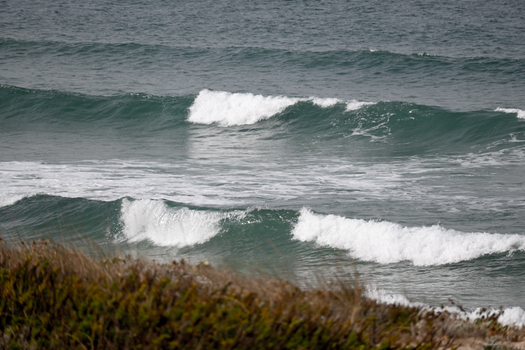 Calm ocean waves rolling onto a quiet, natural beach setting.