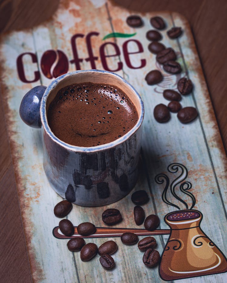 Cup Of Coffee Among Scattered Coffee Beans