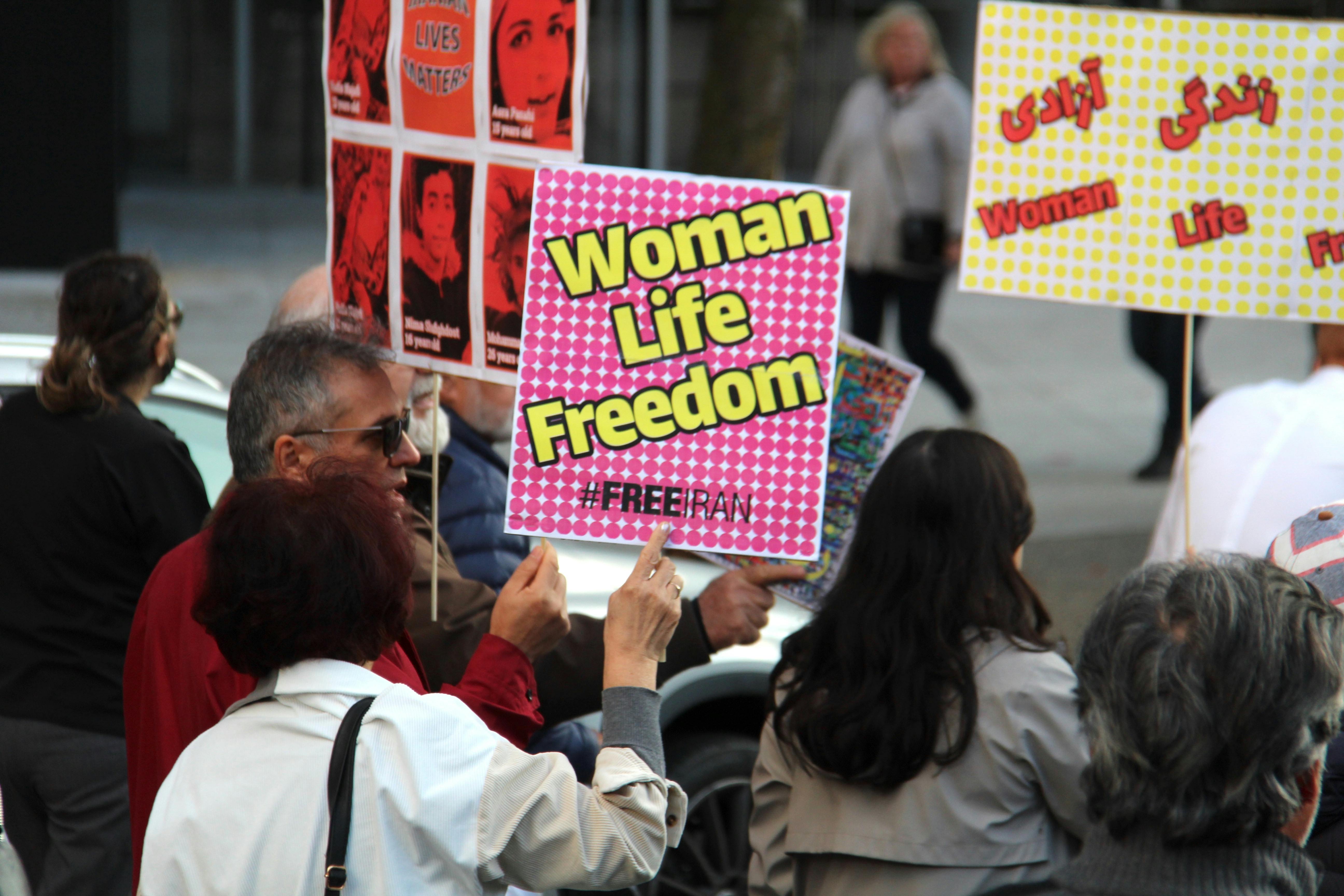 people protesting on street holding posters