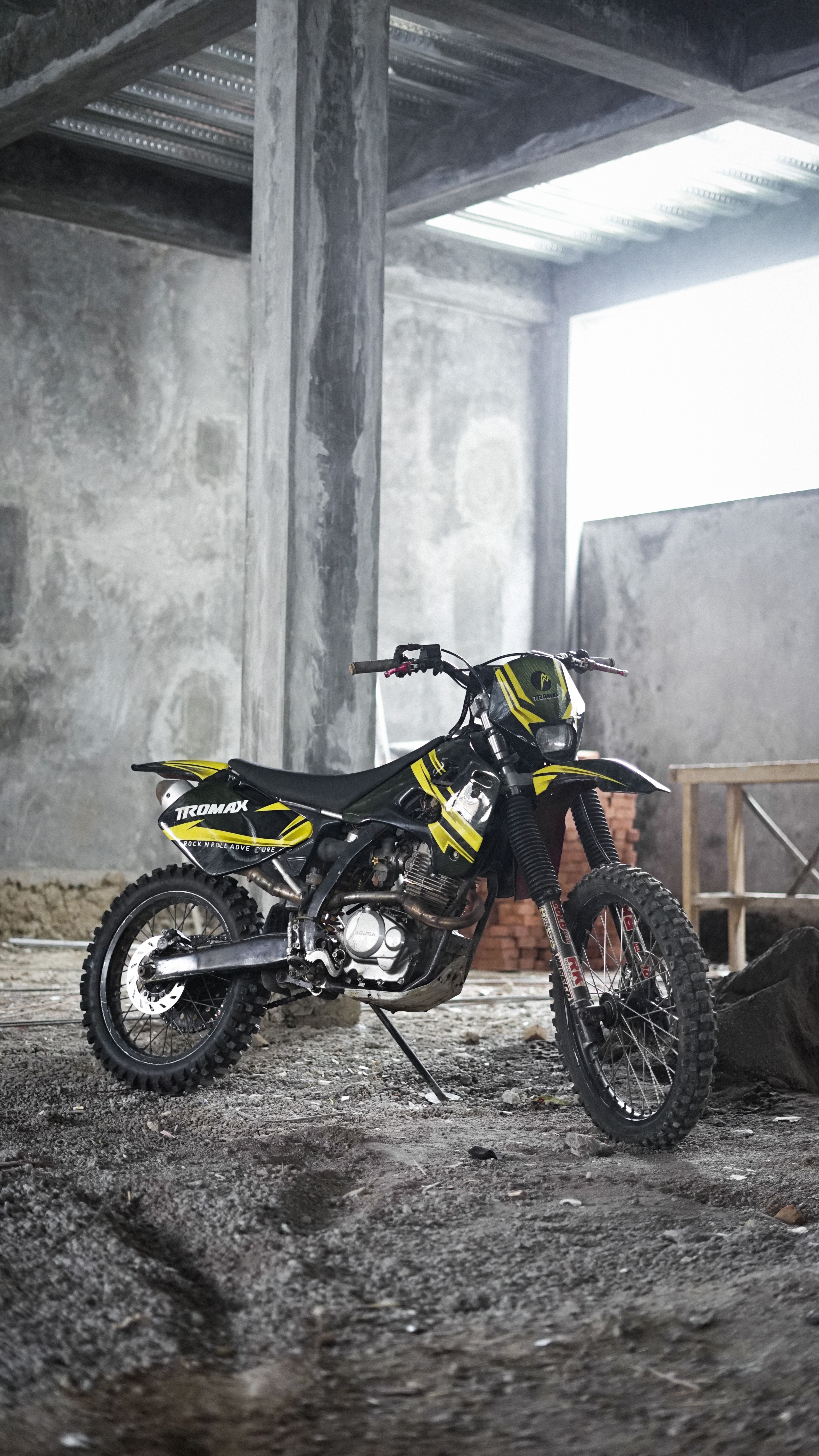 A dirt bike parked inside a concrete industrial building, perfect for adventure enthusiasts.