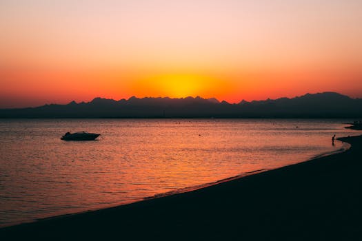 Beautiful silhouette of a boat during sunrise at Safaga beach, showcasing vibrant colors and serene waters.