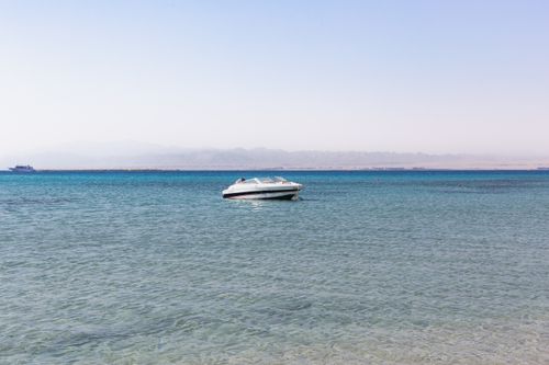 Free A lone speedboat on a calm and clear blue sea with a distant horizon under a clear sky. Stock Photo
