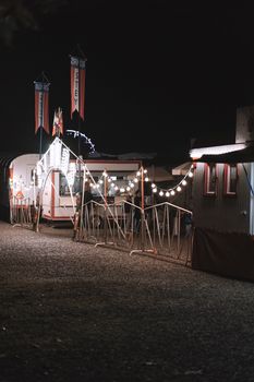 A festival atmosphere at night with string lights illuminating the circus entrance.