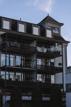 A modern residential building featuring balconies and a dark facade in an outdoor urban setting.