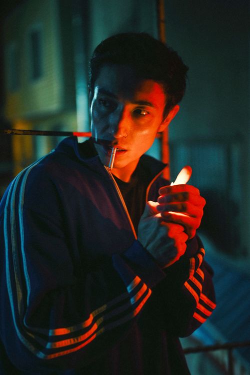 Free A young man smoking at night, illuminated by vibrant lighting for a dramatic effect. Stock Photo
