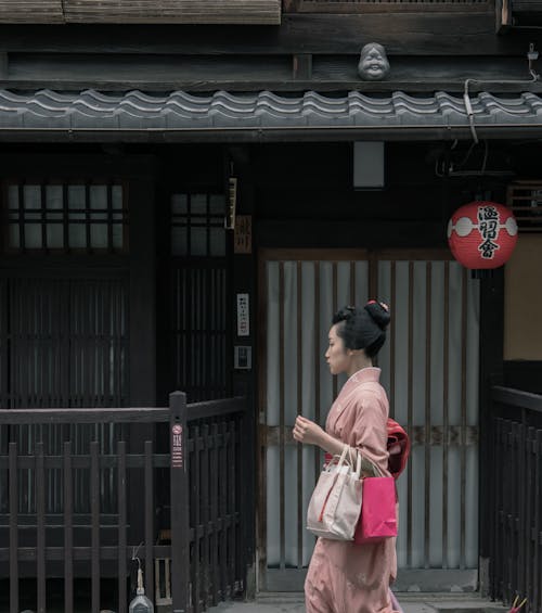 Wanita Mengenakan Kimono Merah Muda Berjalan Dekat Rumah