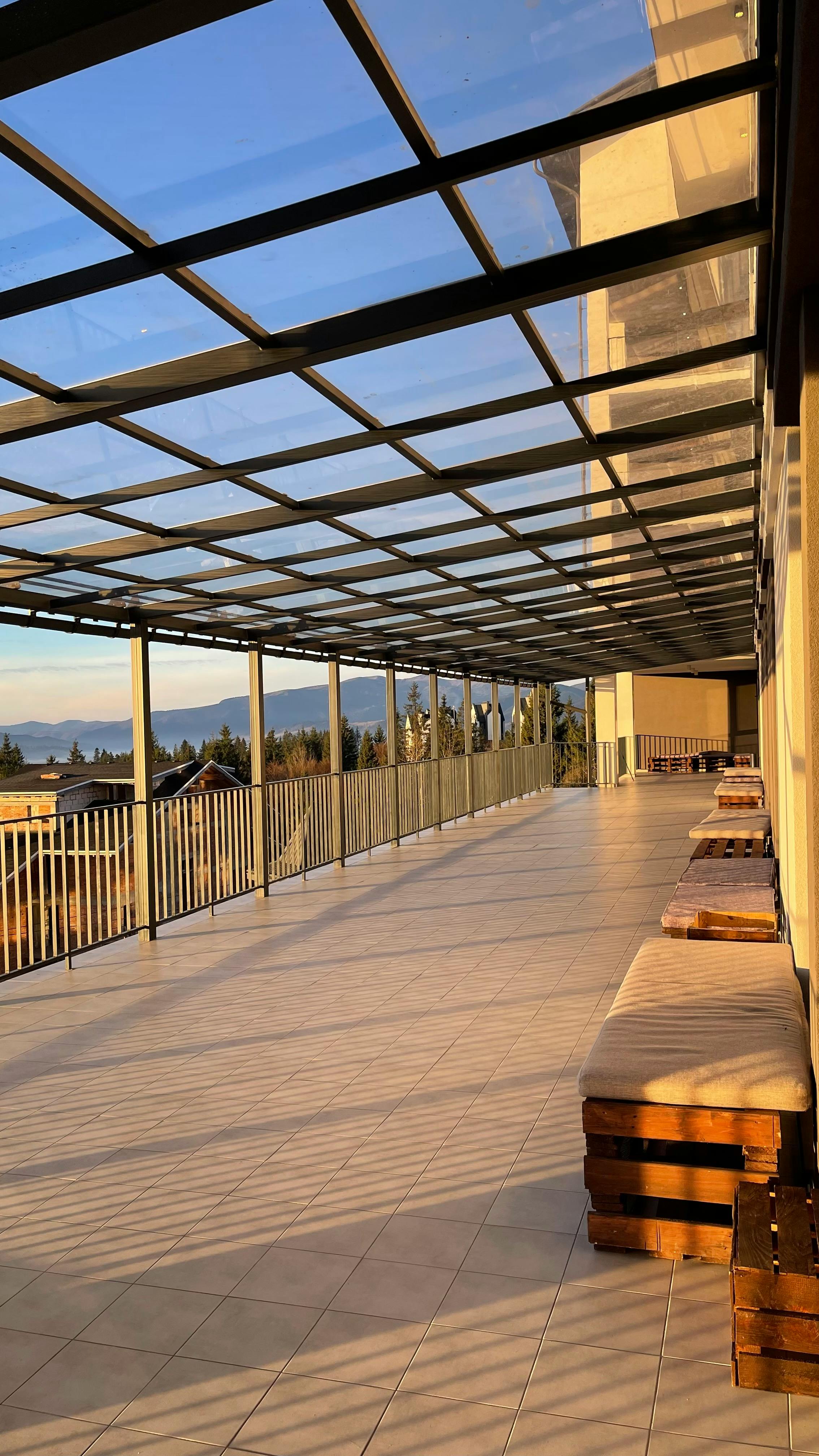 Spacious terrace in Yaremche, Ukraine, with a glass roof and benches, offering scenic mountain views.
