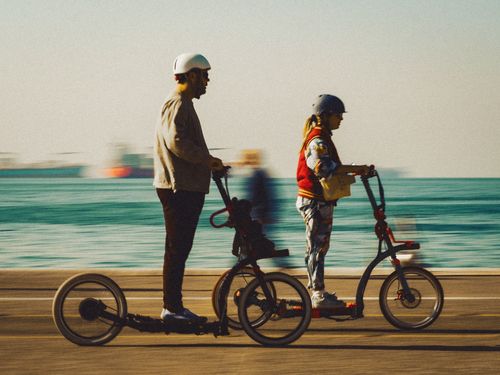Free A man and woman enjoying a sunny day riding electric scooters along the seaside promenade. Stock Photo