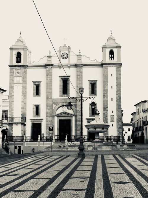 Free A classic church facade in a monochrome urban square with striped pavement. Stock Photo