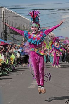 A joyful dancer in vivid costume leaps during a lively street parade, spreading happiness.