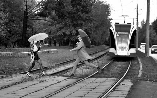 Free A man and woman crossing tram tracks in a stylish black and white cityscape. Stock Photo