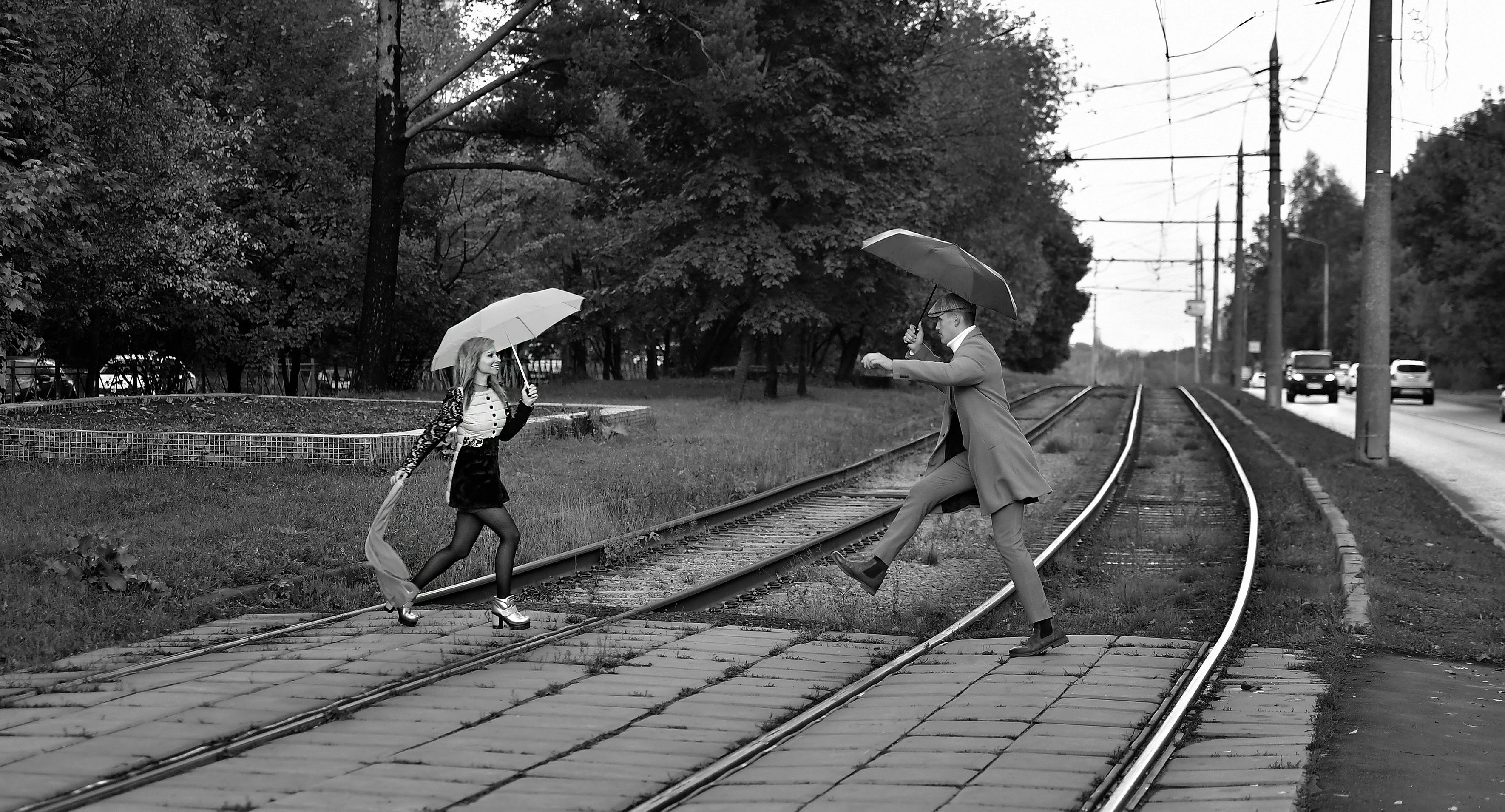 Man and Woman with Umbrellas Crossing Railway · Free Stock Photo