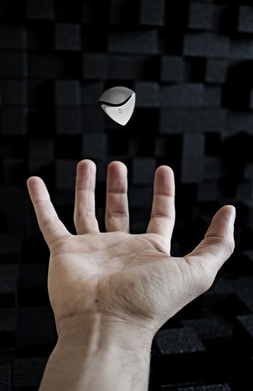 Free A dynamic capture of a hand tossing a guitar pick in the air, set against a dark acoustic foam backdrop. Stock Photo