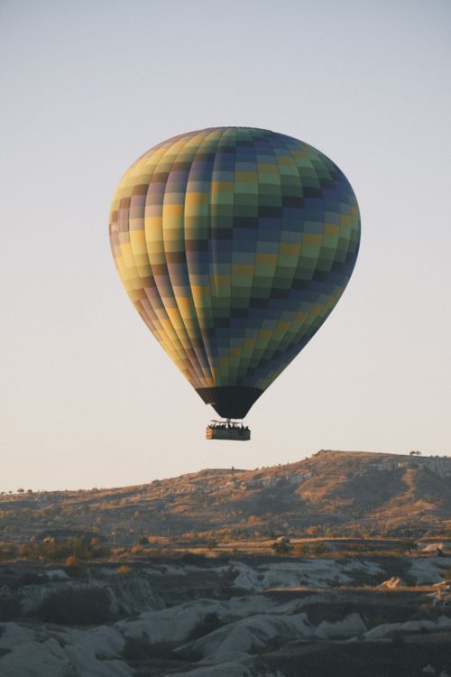 Free A vibrant hot air balloon floats over the unique terrains of Cappadocia at sunset, capturing a stunning travel moment. Stock Photo