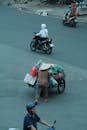 High Angle View of a Road with Cyclists and a Man Wearing Asian Hat Pushing a Traditional Cart