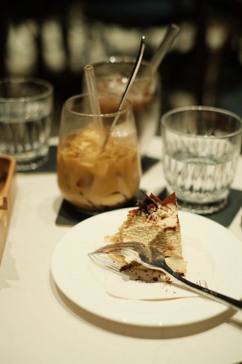 Free A slice of tiramisu on a plate with iced coffee and water, perfect for dessert lovers. Stock Photo