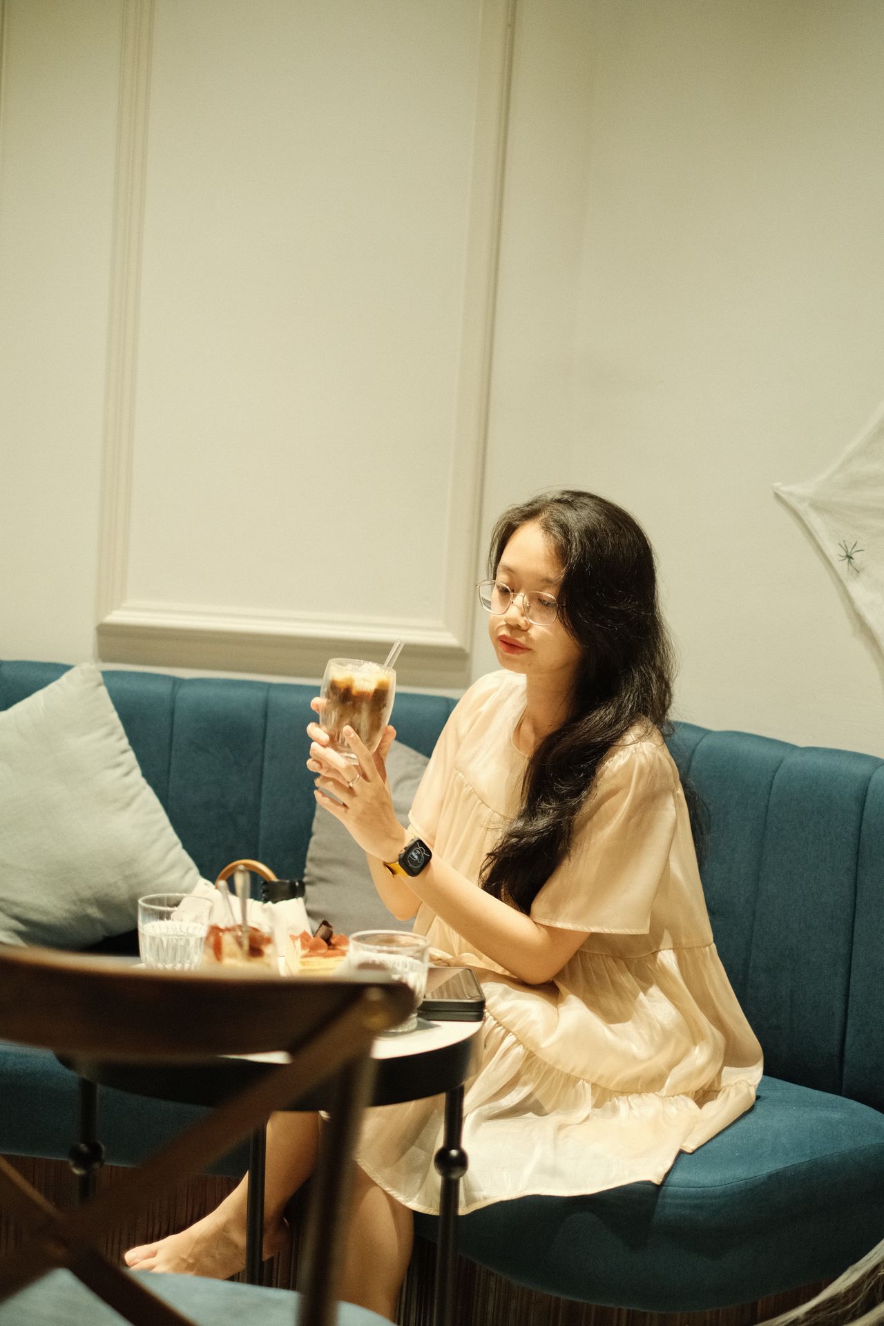 Woman in a cream babydoll dress sitting in a cafe
