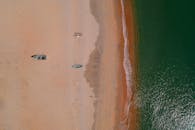 航拍镜头展现了沙滩上的船只和清澈的绿色海浪，突显了夏季的海滨景观