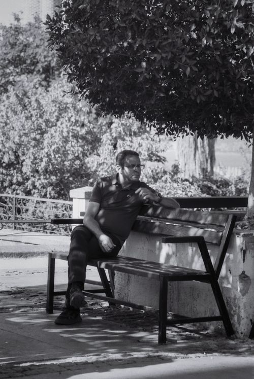 Free A man in deep thought sits on a park bench. Black and white photo capturing a serene moment. Stock Photo