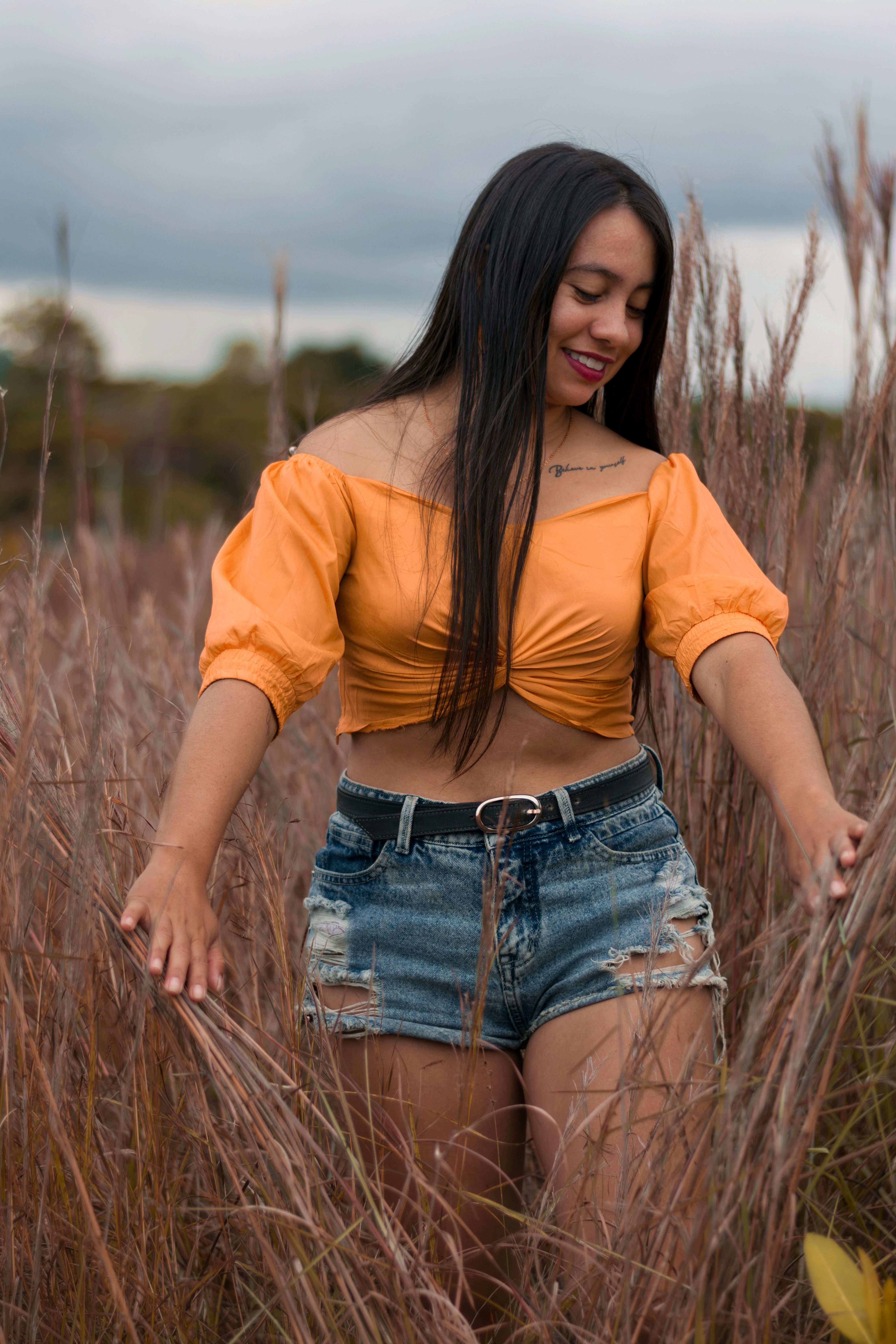 Woman in Orange Crop Top Standing on Tall Grass · Free Stock Photo