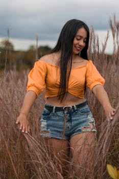 A young woman with long hair and casual style walking through a grassfield in San Agustín, Colombia.