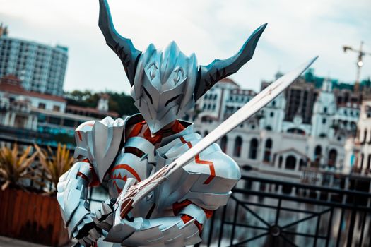 A person in futuristic armor with a sword posing outdoors, showcasing cosplay artistry.