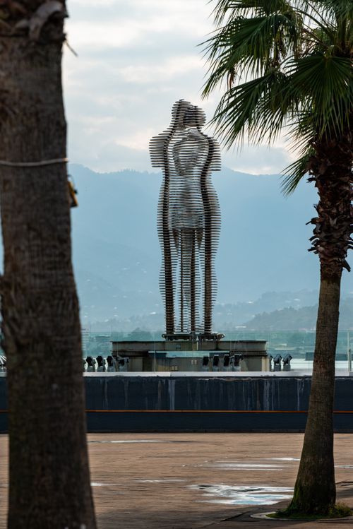 Free Famous revolving sculptures of Ali and Nino in Batumi, Georgia against a mountainous backdrop. Stock Photo