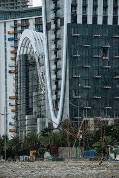 Contemporary facade with scaffolding and palm trees, illustrating urban development.
