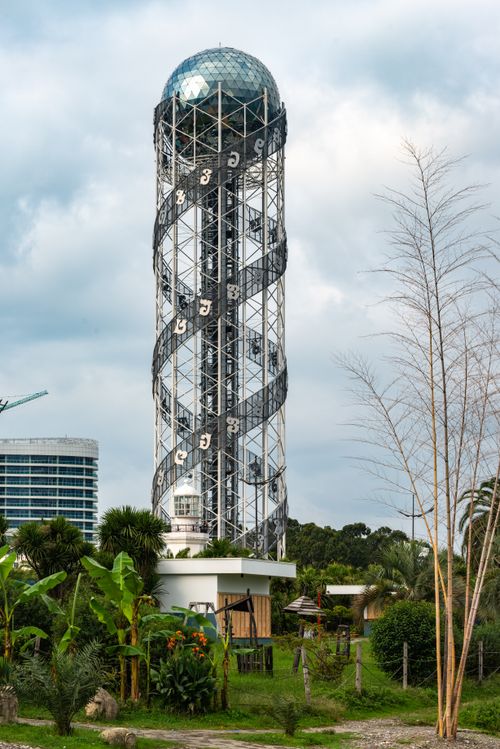 Free View of the iconic Alphabetic Tower in Batumi, Georgia, amidst lush greenery and cityscape. Stock Photo