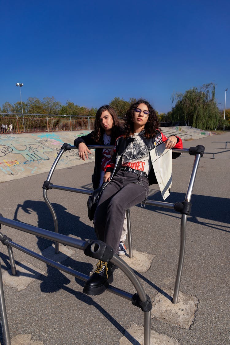 Teenager Couple Sitting On Sport Equipment Outdoors