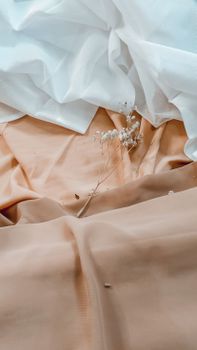A still life of delicate white flowers resting on soft pink and white fabric.