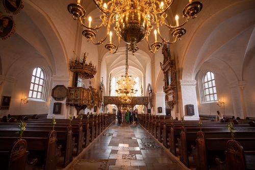 Free Beautiful gothic church interior featuring large chandeliers, pews and ornate details. Captures holy ambiance. Stock Photo