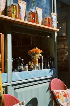 Charming coffee shop with shelves of bags, cozy seating, and a vase of flowers.