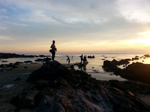 Ücretsiz Gri Gökyüzü Altında Deniz Kıyısı üzerinde Insan Silüeti Stok Fotoğraflar