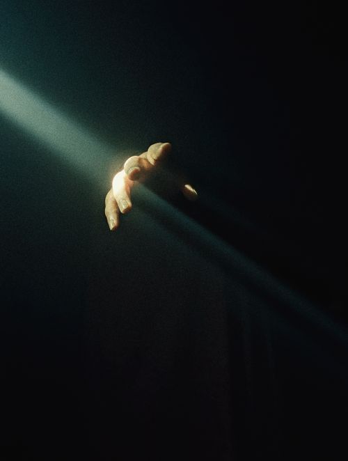 Free A dramatic scene of a hand reaching into a beam of light, symbolizing hope and mystery. Stock Photo