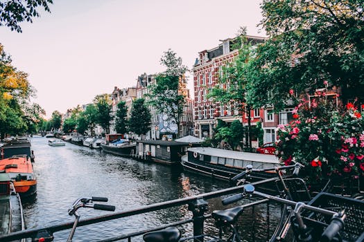 Charming view of Amsterdam canal lined with historic buildings and bicycles at sunset. by Liam Gant