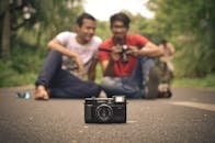 Men Sitting on the Road and Photographing a Camera
