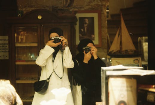Two women wearing hijabs take pictures with cameras in a museum setting.