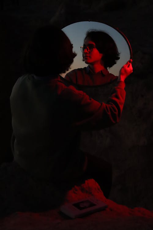 Woman Holding a Mirror and Looking at her Reflection 
