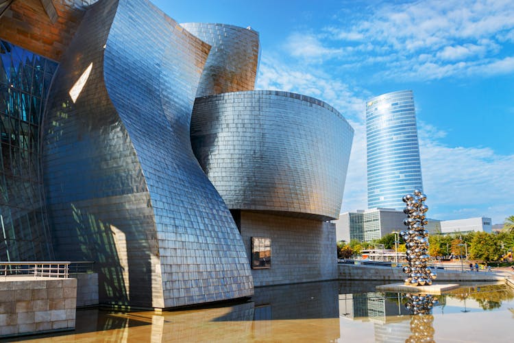 Futuristic Curved Building Reflecting In Murky Pool Water