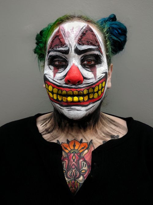 Free A vivid portrait of a person in clown makeup and colorful hair, showcasing detailed tattoos. Stock Photo