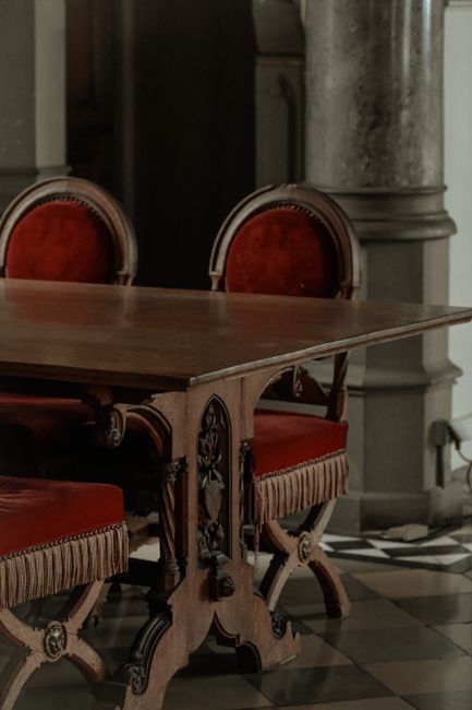 Ornate wooden table with vintage style chairs in classic indoor setting.