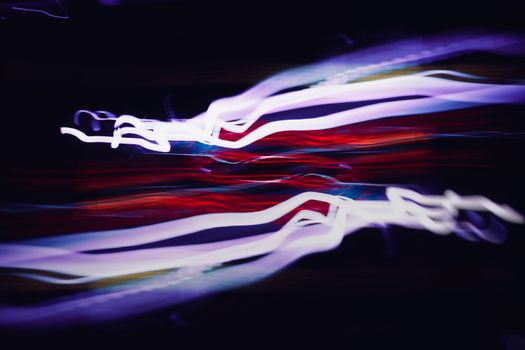 Vibrant light streaks in motion against a dark backdrop create a dynamic abstract effect.