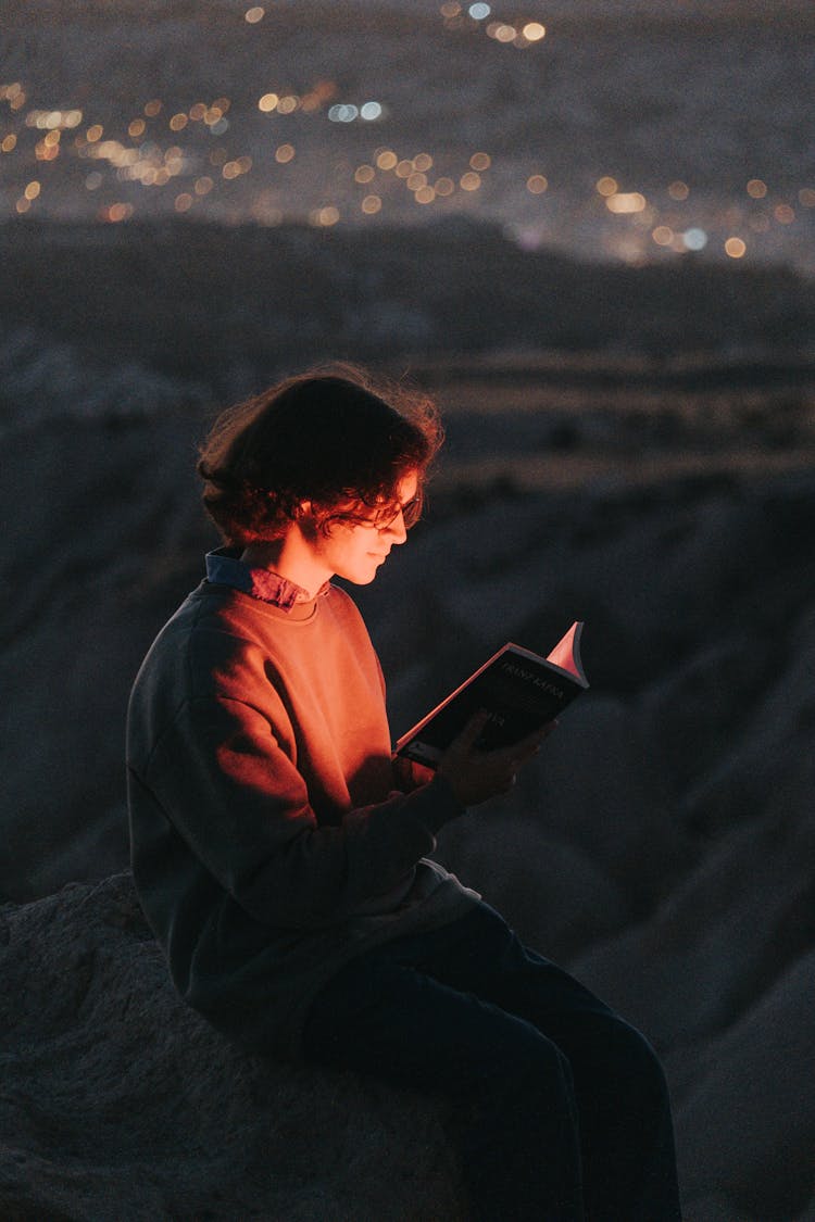 Man Reading Book In Outdoors At Night