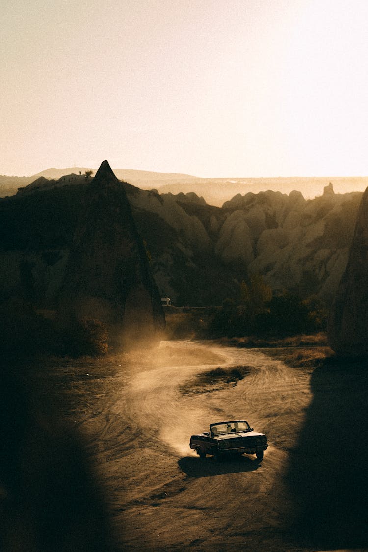 Retro Car Driving In Mountain Landscape On Sunset