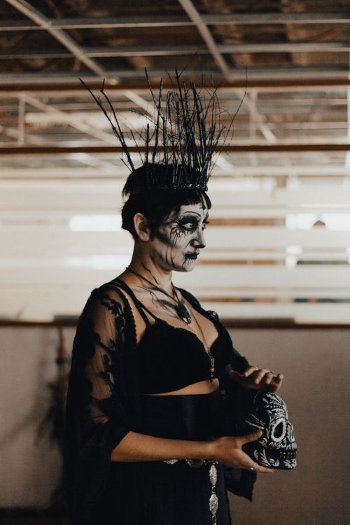 Free A woman in costume with intense makeup holds a decorated skull, evoking a Halloween theme. Stock Photo