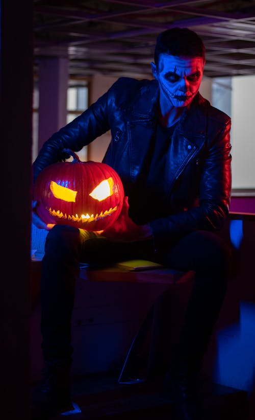 Man in a Halloween Makeup Holding a Pumpkin Lantern
